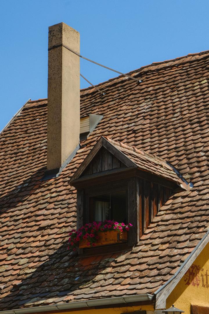 Weathered brick chimney above a tiled roof